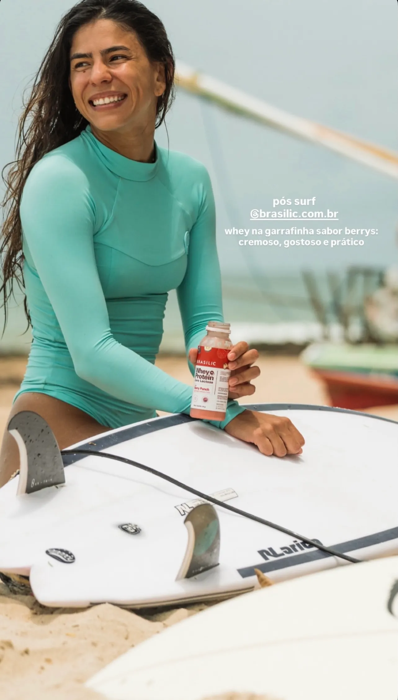 Cliente segurando o Whey Berry Punch na praia, pós surf